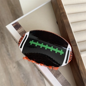 Détail d'une pince à cheveux en forme de rugby noir avec des lignes de sport colorées