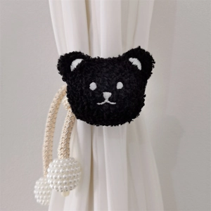 Detail of plush black bear curtain tieback with woven rope and white pearl beads