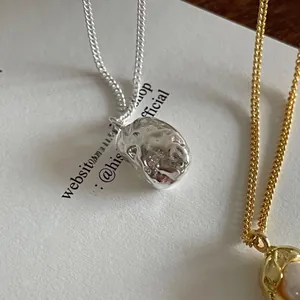 Macro detail of S925 sterling silver textured pendant and gold pearl bead necklace