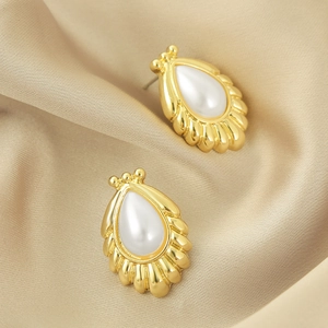 Detail of vintage teardrop pearl earrings with pleated gold alloy frame on silk fabric