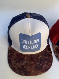 Detail of color-block hip hop cap showing the embroidered slogan and textured brim