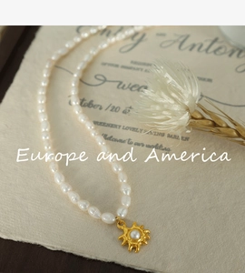 Detail of freshwater pearl necklace with gold sunflower pendant on vintage paper card