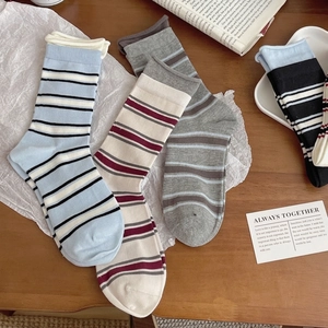 Striped cotton crew socks in multiple colors laid on a wooden desk for a casual look