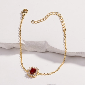 Détail macro du bracelet plaqué or avec pierre de zircon rouge et fermoir mousqueton