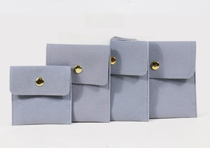 Détail de quatre pochettes à bijoux en velours gris-bleu avec boutons-pression dorés