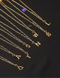 Close-up of gold-plated brass alphabet pendants with bamboo texture on paperclip chains