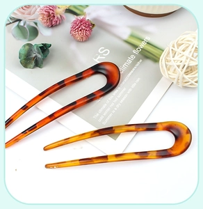 Close-up of dual tortoiseshell U-shaped hair pins with smooth resin finish on a white background