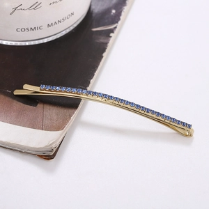 Close-up of a long gold hair clip with sparkling blue rhinestones in a lifestyle setting