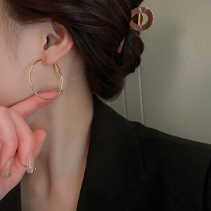 Gros plan de boucles d'oreilles créoles dorées portées par un mannequin en costume