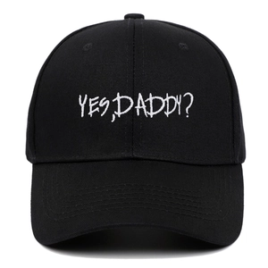 Close-up of white YES DADDY embroidery on black cotton twill baseball cap fabric