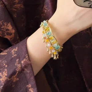 Detail of New Chinese style gold bangle with tassels and blue yellow beads on wrist
