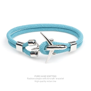 Detail of light blue woven bracelet featuring a silver aircraft charm on white background