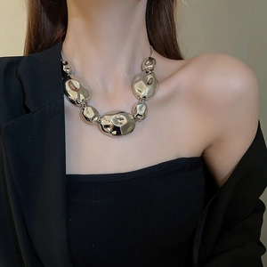 Close-up of silver-toned statement necklace featuring bold crumpled-style metal beads