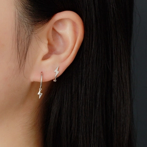 Macro shot of S925 sterling silver lightning bolt hoop earrings on a model's ear