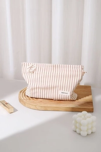 Dettaglio della borsa da toilette a righe bianche e rosse con etichetta su base in legno