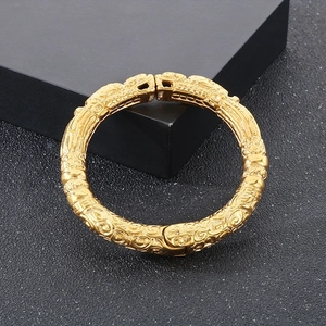 Detail of golden bangle showing intricate embossed dragon and cloud patterns with a vintage finish