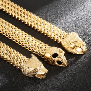 Macro shot of gold punk bracelets featuring wolf, skull and lion head charms on black surface