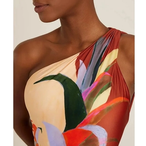 Detail of asymmetrical shoulder pleats on a one-piece swimsuit with tropical floral print