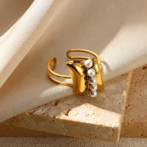 Detail of gold pearl ring with five small pearls on beige silk and stone background