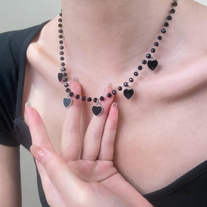 Close-up of black beaded necklace with five heart-shaped silver-trimmed pendants