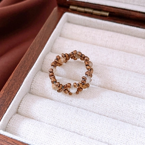 Detailed shot of retro stone and bronze glass beads hand-woven on a vintage stretch ring