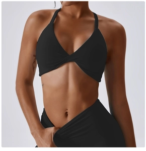 Detail of cross-pleated sports bra and high-waisted leggings in matte black stretch fabric