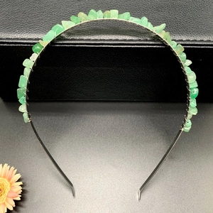 Macro detail of handmade silver headband with green raw crystal stones wire-wrapped firmly