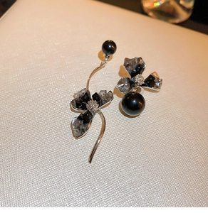 Detailed close-up of asymmetric flower earrings with black crystals and pearls