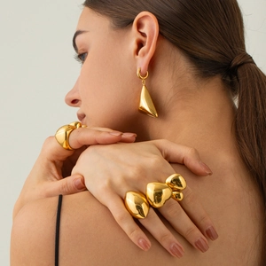 Dettaglio di anelli e orecchini in acciaio dorato 18k con motivo geometrico trapuntato chic