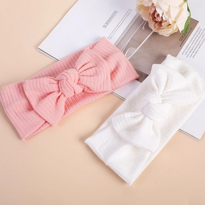Detailed view of pink and white ribbed knit baby headbands with large bow accents