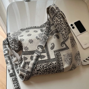Detailed close-up of paisley print canvas bag with adjustable strap and brand label
