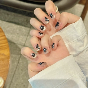 Detailed view of handmade cat eye nails with hand-painted black flowers and small crystals