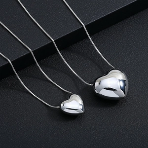 Close-up of polished 3D heart pendants in two sizes on sleek silver box chains