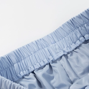 Detail of light blue satin shorts featuring an elastic waistband and premium stitching