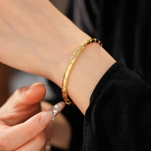 Detailed view of a gold arrow pattern bracelet featuring interlocking chevron metal segments