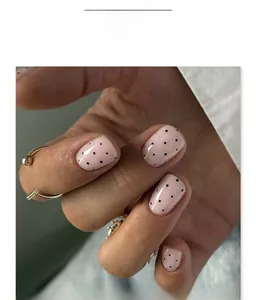 Close-up of pink short square press-on nails with black polka dot patterns
