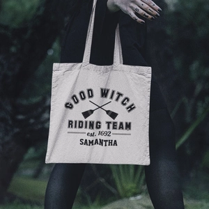 Detail of canvas tote bag with Good Witch Riding Team print held by a model