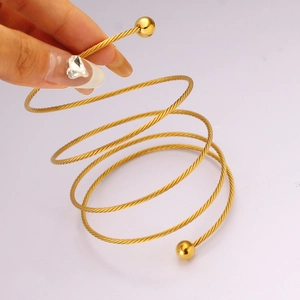 Vista dettagliata della flessibilità del bracciale a spirale dorato con trama intrecciata e sfere