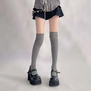 Detail of gray knitted over-knee socks with vertical ribbed texture and slouchy style