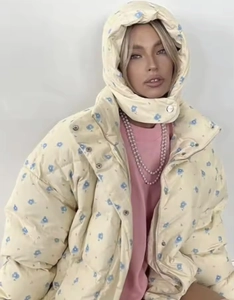 Detailed close-up of drawstring floral puffer jacket with blue patterns on light yellow
