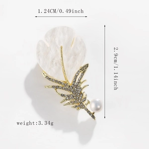 Macro view of feather brooch showing gold metal, resin marble texture and clear rhinestones