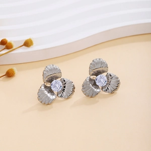 Macro detail of silver flower earrings with textured petals and center zircon stone