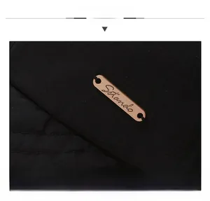 Détail d'une casquette en sergé noir avec plaque logo métal or rose et coutures fines