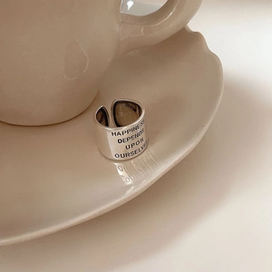 Détail d'une bague en argent 925 gravée du texte 'HAPPINESS DEPENDS UPON OURSELVES' en gros plan