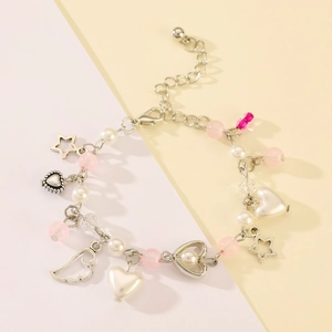 Close-up of pearl charm bracelet with silver star, heart, and wing pendants on pastel background