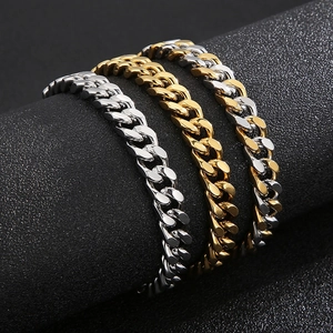 Polished stainless steel Cuban chain bracelets in silver and gold on a display stand