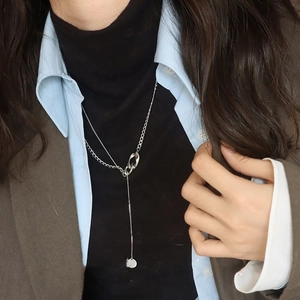 Gros plan d'un collier multicouche en argent en forme de Y porté par un mannequin
