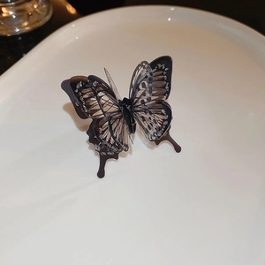 Detailed close-up of a butterfly ring with gold plating and pearl on a white plate