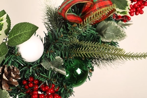 Detail of Christmas wreath featuring frosted pinecones, red berries, and festive plaid bow
