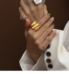Nahaufnahme eines breiten goldenen Edelstahlrings mit Fingerabdruck-Struktur am Finger
